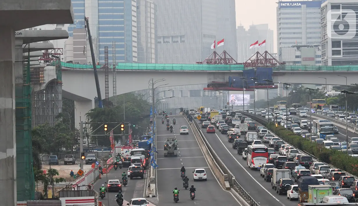 Kendaraan melintas berlatar pembangunan bentangan beton lintasan LRT di Jalan Gatot Subroto Jakarta, Kamis (7/11/2019). Saat ini pembangunan tiang pancang yang membentang di atas ruas jalan tol tersebut sudah tersambung. (Liputan6.com/Immanuel Antonius)
