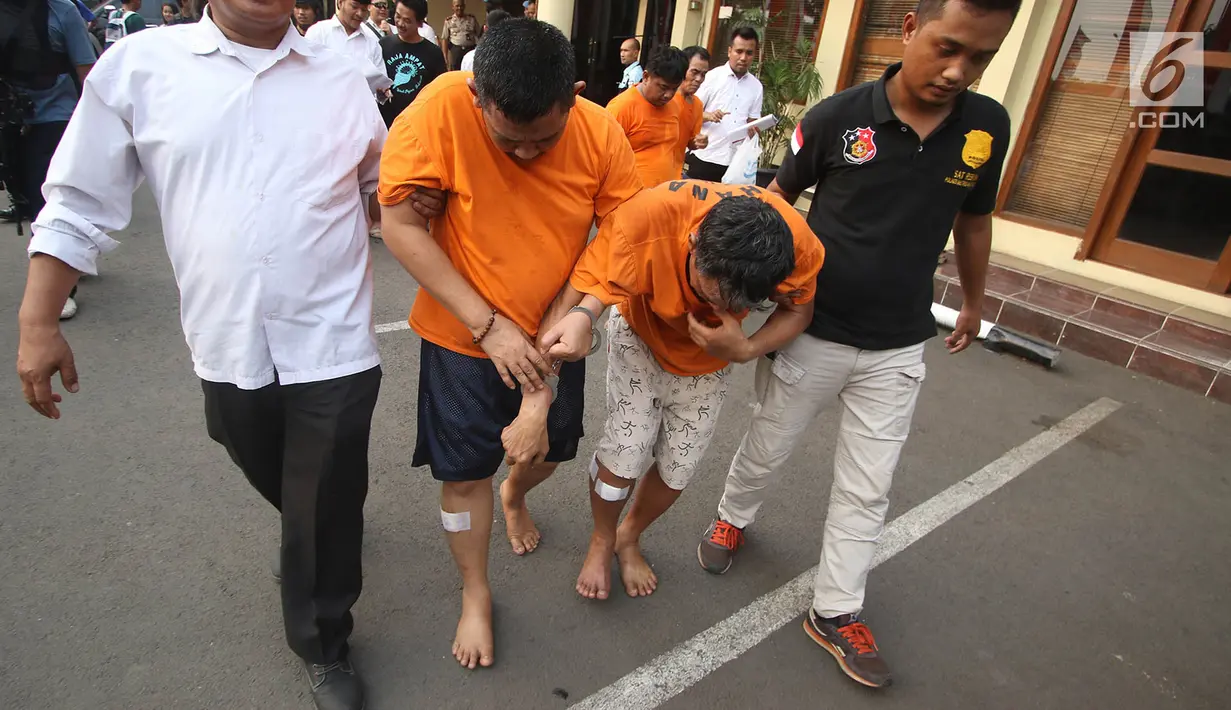 Petugas membawa tersangka beserta barang bukti kasus penipuan dengan ATM di Mapolres Metro Jakarta Barat, Senin (14/8). (Liputan6.com/Immanuel Antonius)