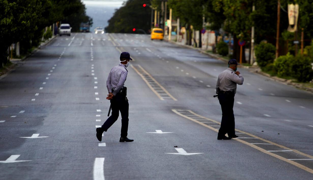 Polisi yang mengenakan masker berjalan di jalanan kosong saat penerapan jam malam di Havana, Kuba, Selasa (1/9/2020). Otoritas Kuba menerapkan lockdown selama 15 hari di Havana untuk keluar dari penularan COVID-19 tingkat rendah tetapi terus-menerus. (AP Photo/Ramon Espinosa)