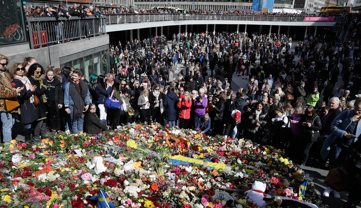 Orang-orang berkerumun di lokasi terjadinya serangan truk di Stockholm, Swedia, Minggu (9/4). Sebuah truk yang dibajak menabrakkan diri ke kerumunan pejalan kaki pada Sabtu (8/4) dan menewaskan empat orang. (AP Photo / Markus Schreiber)