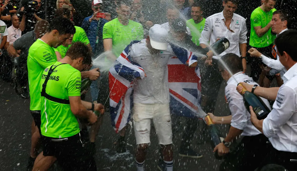 Pembalap asal Inggris dari tim Marcedes, Lewis Hamilton membawa bendera negaranya merayakan kemenangannya meraih juara dunia F1 untuk yang ke empat kalinya di Autodromo Hermanos Rodrigue, Meksiko (29/10). (AP Photo/Marco Ugarte)