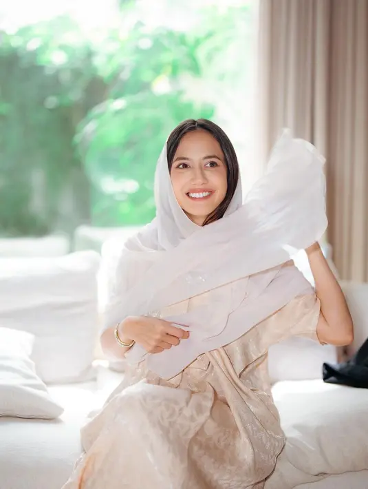 Penampilan Pevita Pearce di foto ini bisa kamu jadikan inspirasi outfit bukber. Ia tampil mengenakan gamis lengan pendek yang mengkilap, menambah nuansa mewah pada tampilan yang sederhana. Pevita menambahkan selendang putih polos untuk menutupi kepalanya. [Foto: Instagram/pevpearce]