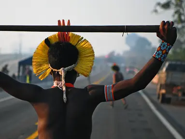 Masyarakat suku Kayapo memegang tongkat saat memblokir jalan raya utama Trans-Amazonian di Negara Bagian Para, Brasil (17/8/2020). Aksi tersebut dilakukan di tengah pandemi Covid-19 ini sebagai unjuk rasa adat. (AFP Photo/Carl De  Souza)