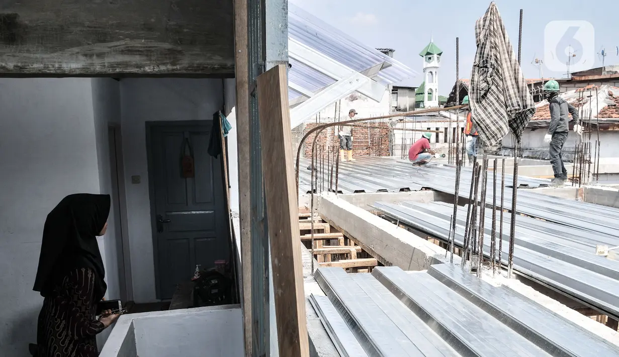 Wiwiek saat menyaksikan pekerja yang sedang membangun gedung sekolah tepat di depan rumahnya di Jalan Cempaka Baru I, RT 015/003, Kemayoran, Jakarta, Senin (31/8/2020). Pembangunan itu menutup akses jalur keluar masuk dan harus melewati pintu samping. (merdeka.com/Iqbal S Nugroho)
