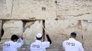 Pekerja Tembok Barat menghapus pesan dan doa, yang ditulis di selembar kertas oleh ribuan orang yang "ditujukan kepada Tuhan", dari celah-celah situs suci Yahudi di Kota Tua Yerusalem (30/3/2022). Pembersihan sebagai persiapan untuk liburan Paskah Yahudi yang akan datang. (AFP/Hazem Bader)