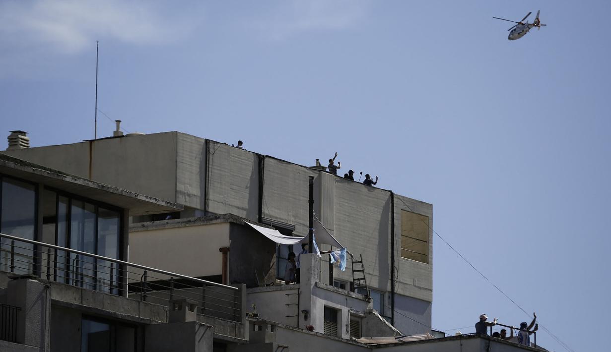 Helikopter yang membawa beberapa anggota timnas Argentina melintas saat parade kemenangan Piala Dunia 2022 di provinsi Buenos Aires, pada 20 Desember 2022. Messi dan kolega terpaksa dievakuasi karena bus yang mereka gunakan tak bisa mencapai lokasi yang direncanakan akibat membeludaknya warga di jalanan. (AFP/Emiliano Lasalvia)