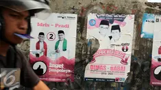 Warga melintas di depan alat peraga kampanye Pilkada Kota Depok, Jawa Barat, Rabu (2/12). Kota Depok menjadi salah satu daerah yang akan melaksanakan Pilkada serentak pada 9 Desember mendatang. (Liputan6.com/Helmi Fithriansyah)