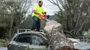 Seorang pria menebang batang pohon yang menimpa mobilnya usai terjadi badai di Elon, Virginia (16/4). Akibat badai ini sejumlah rumah rusak berat. (Jay Westcott/The News & Advance via AP)