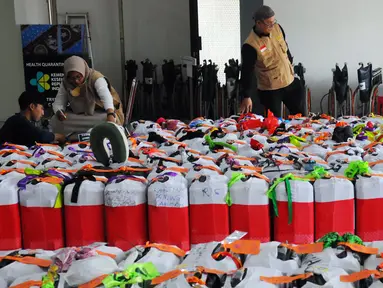 Petugas melakukan pengecekan koper para jemaah haji di Asrama Haji Pondok Gede, Jakarta, Selasa (23/5/2023). Keberangkatan jemaah haji kloter pertama akan dimulai pada Rabu, 24 Mei 2023. (merdeka.com/Imam Buhori)