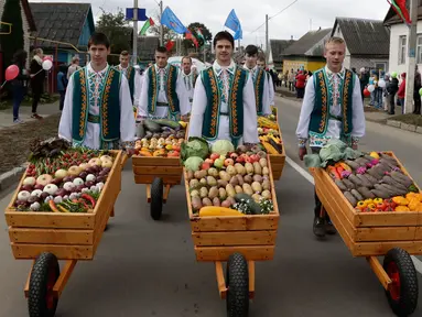 Sejumlah pria mengenakan pakaian adat Belarusia mendorong gerobak berisikan sayuran dalam Festival Dozynki di Minsk, Belarusia, Minggu (7/10). Warga Belarusian rayakan pengumpulan hasil panen dalam festival ini. (AP Photo/Sergei Grits)