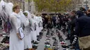 Perempuan berpakaian seperti malaikat berdiri di antara sepatu yang dipajang di place de la Republique, Prancis, sebagai tanda solidaritas karena pawai lingkungan di Paris dibatalkan jelang KTT Perubahan Iklim, Minggu (29/11).(AFP PHOTO/Miguel Medina)