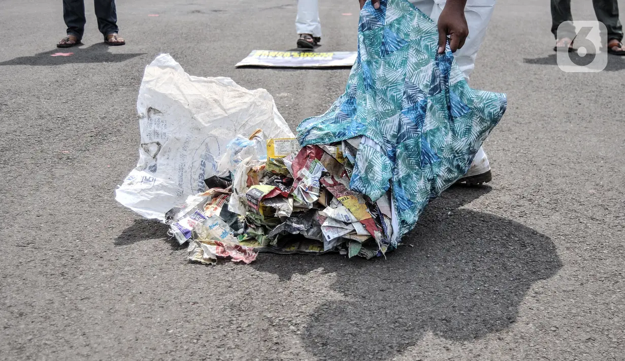 Aktivis menunjukkan limbah hasil temuan selama investigasi di daerah Sungai Brantas, Bengawan Solo, Citarum, dan Ciujung saat aksi "Sampah Impor Bunuh Sungai Pulau Jawa" di kawasan Patung Kuda, Monas, Jakarta, Senin (3/5/2021). (merdeka.com/Iqbal S. Nugroho)