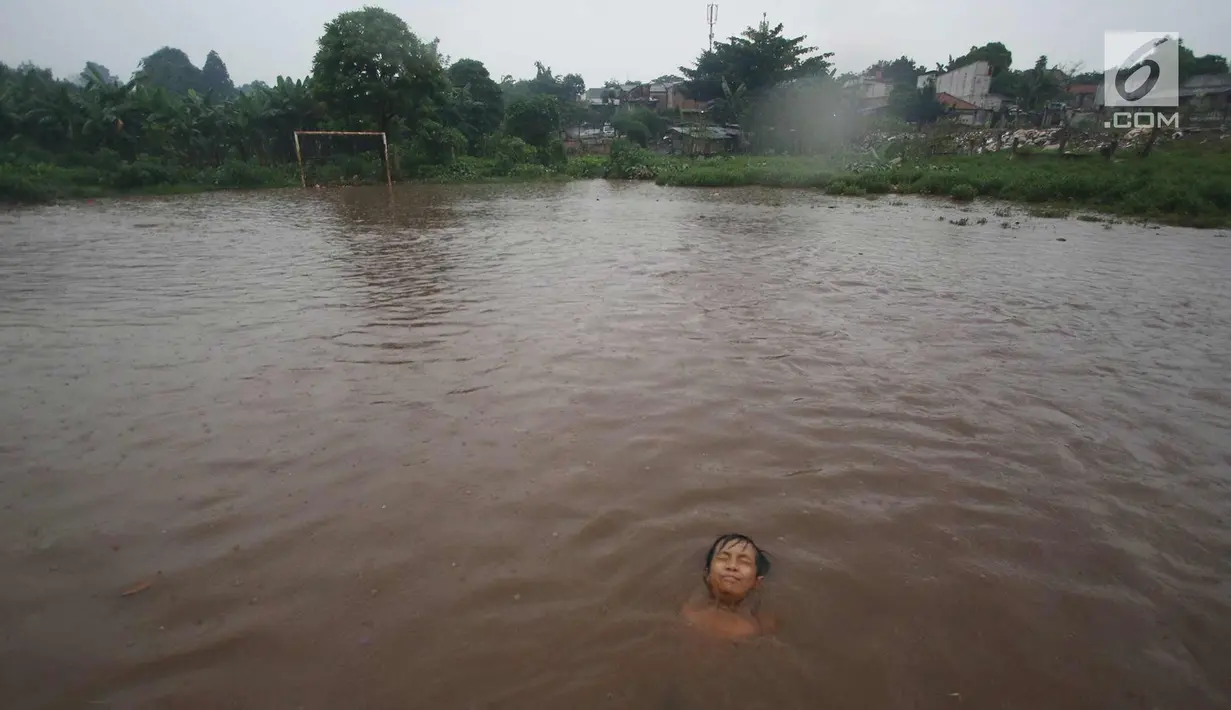 Seorang anak bermain di lapangan yang terendam banjir di kawasan Kemang, Jakarta, Kamis (16/11). Tingginya intensitas hujan dan pesatnya pembangunan menyebabkan kawasan tersebut langganan banjir karena luapan Kali Krukut. (Liputan6.com/Immanuel Antonius)