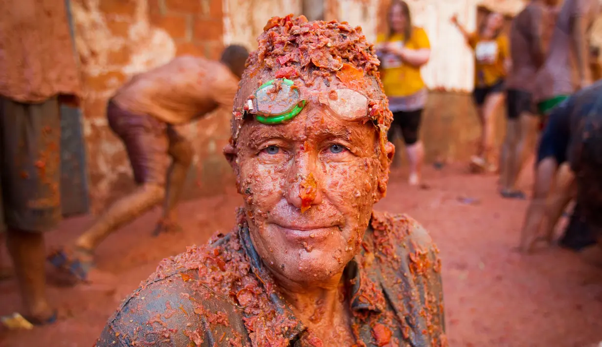 Seorang peserta bersuka ria dengan tomat yang hancur saat berpartisipasi dalam festival tahunan "Tomatina" di Bunol, salah satu kota di timur Spanyol, Rabu (29/8/2019). Perang tomat yang penuh kehebohan itu rutin diadakan setiap Rabu terakhir bulan Agustus. (JAIME REINA / AFP)