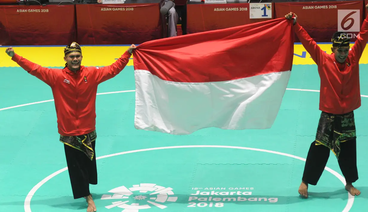 Pesilat Indonesia Yolla Primadona Jumpil dan Hendy membawa bendera setelah memenangi nomor seni ganda putra Asian Games 2018 di Padepokan Pencak Silat, TMII, Senin (27/8). Tim silat Indonesia menyabet medali emas dengan skor 580. (Merdeka.com/Arie Basuki)