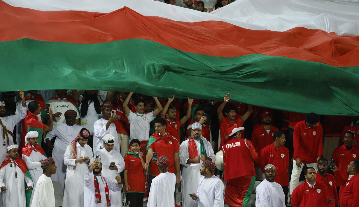 Para pendukung Oman membentangkan bendera raksasa saat Timnas Oman menghadapi Kirgistan pada laga ketiga Grup F Piala Asia 2023 di Abdullah bin Khalifa Stadium, Doha, Qatar, Kamis (25/1/2024). (AFP/Karim Jaafar)