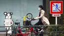 Seorang wanita yang mengenakan masker untuk membantu mengekang penyebaran COVID-19 mengendarai sepeda di Tokyo, Jepang, Senin (2/11/2020). Tokyo mengonfirmasi lebih dari 80 kasus baru COVID-19 pada 2 Oktober 2020. (AP Photo/Eugene Hoshiko)