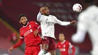 Pemain Liverpool, Joe Gomez, duel udara dengan striker Arsenal, Alexandre Lacazette, pada laga Liga Inggris di Stadion Anfield, Senin (28/9/2020). Liverpool menang dengan skor 3-1. (Paul Ellis/Pool via AP)