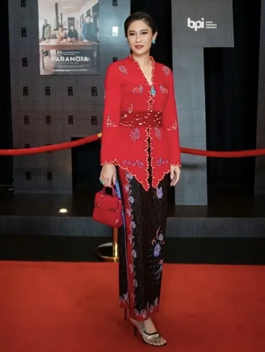 Dian Sastrowardoyo tampil serba merah dengan kebaya modern dari brand Sejauh Mata Memandang, serasi dengan mini hand bagnya.  Lengkap dengan kait lilit hitamnya. (@therealdisastr)