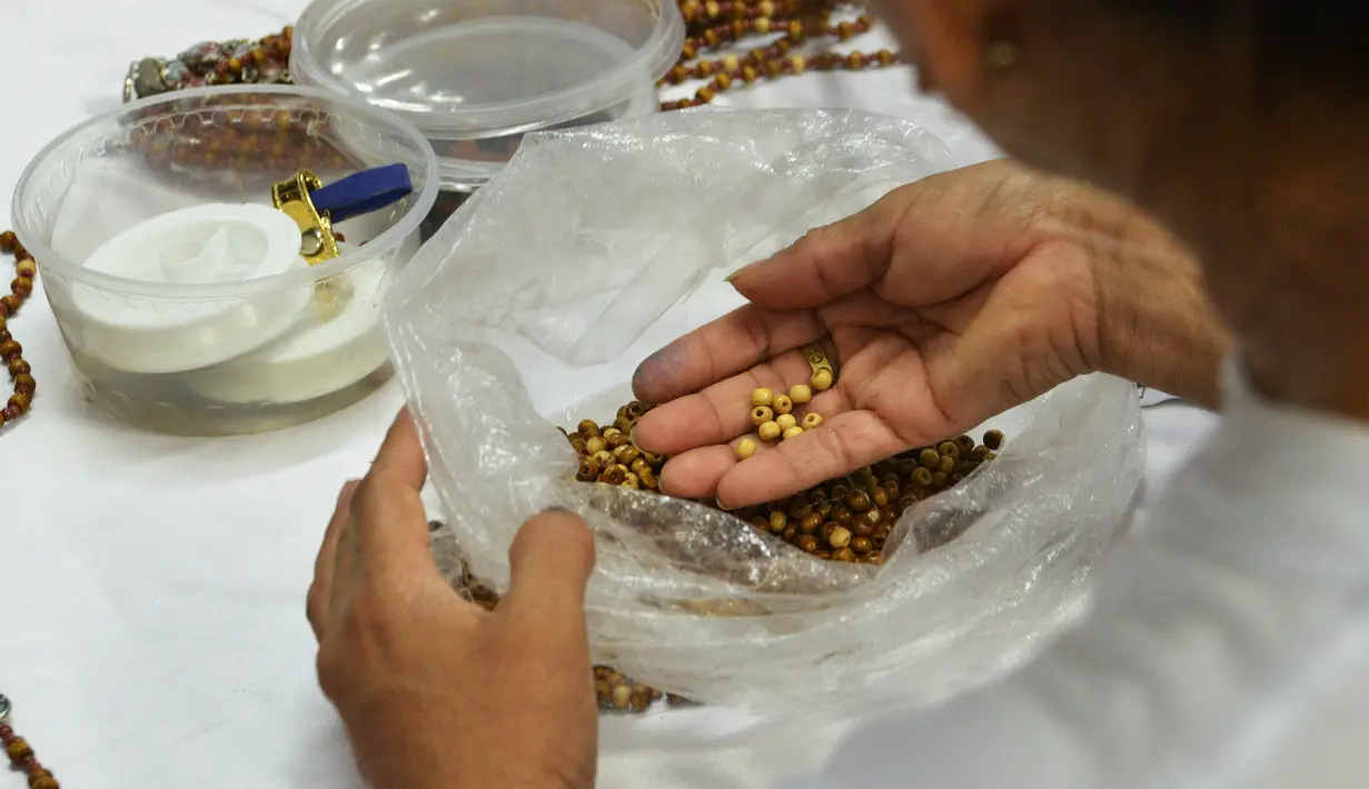 Seorang narapidana di penjara Wanita Virgen de Fatima memilih manik-manik untuk membuat rosario kayu di Lima, Peru (12/1). (AFP Photo/Cris Bouroncle)