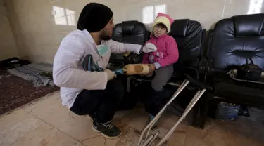 Seorang pekerja pembuat anggota badan buatan, Khamis (kiri) saat memasangkan kaki palsu kepada seorang bocah di kota Maaret al - Numan di provinsi Idlib , Suriah 20 Maret 2016. (REUTERS / Khalil Ashawi)