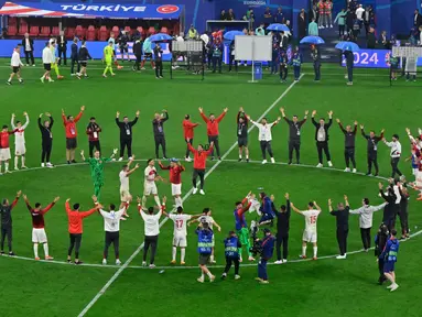 Para pemain dan anggota tim Turki merayakan kemenangan laga babak 16 besar Euro 2024 melawan Austria di Red Bull Arena, Leipzig, pada 2 Juli 2024 atau Rabu 3 Juli 2024 dini hari. (JOHN MACDOUGALL/AFP)