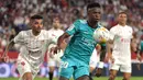 Penyerang Real Madrid Vinicius Junior (kanan) bersaing dengan pemain depan Sevilla Jesus Manuel Corona alias Tecatito pada lanjutan Liga Spanyol di stadion Ramon Sanchez Pizjuan, Senin (18/4/2022) dini hari WIB. Real Madrid sukses menaklukkan Sevilla 3-2. (CRISTINA QUICLER / AFP)