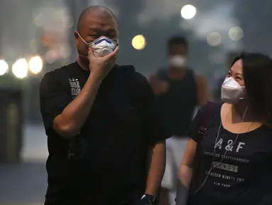Sejumlah warga memakai masker saat berjalan di pusat perbelanjaan Orchard Road, Singapura (25/9/2015). Menurut Badan Lingkungan Nasional Singapura kabut Polutan Standar Indeks (PSI) mencapai tinggi 341 pada hari Jumat. (REUTERS/Edgar Su)