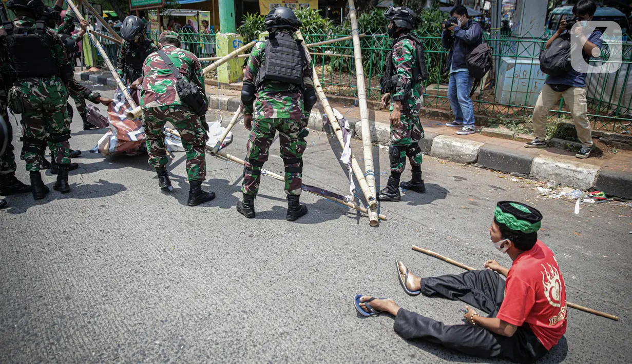 Seorang warga meminta anggota TNI untuk tidak mencopot paksa baliho Rizieq Shihab yang terpasang di sekitar kawasan Petamburan, Jakarta, Jumat (20/11/2020). Pencopotan dilakukan karena menyalahi aturan yang telah ditetapkan. (Liputan6.com/Faizal Fanani)