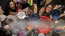 Orang-orang mengisi ember dan mangkuk mereka saat perang air tahunan di jalan-jalan lingkungan Vallecas, Madrid, Spanyol, 17 Juli 2022. Senjata yang diizinkan dalam acara ini adalah pistol dan ember air. (AP Photo/Manu Fernandez)