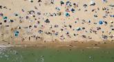 Foto udara menunjukkan orang-orang bermain dan bersantai di bawah sinar matahari di Pantai Bournemouth, Selatan Inggris pada Selasa 26 Mei 2026, saat kondisi gelombang panas menyebar ke sebagian wilayah tenggara Inggris dan London. (JUSTIN TALLIS/AFP)