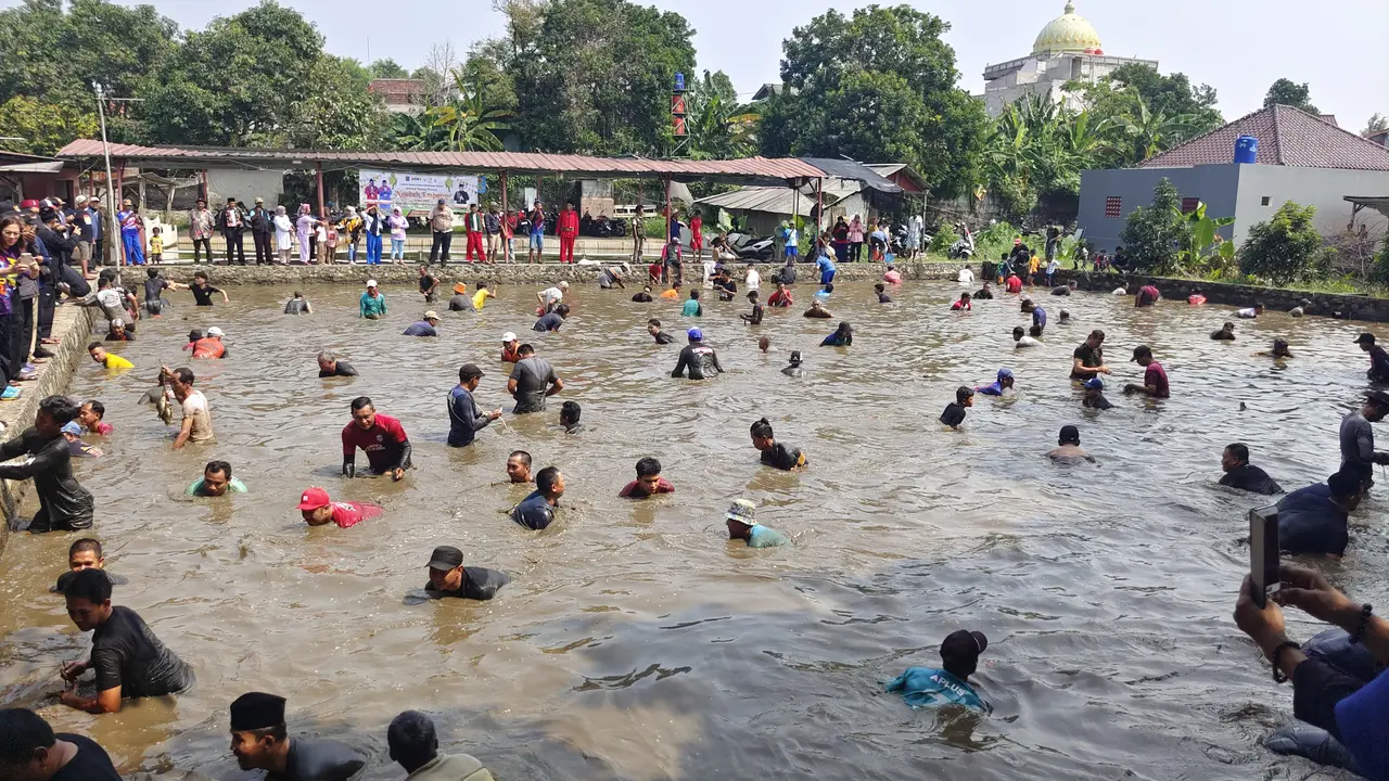 Sejumlah warga ngubek empang atau mencari ikan di dalam kolam pada rangkaian lebaran Depok di Kecamatan Bojongsari, Kota Depok.
