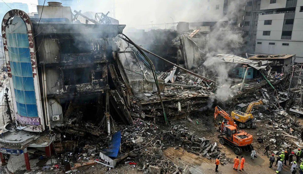 Petugas penyelamat mencari korban di antara puing-puing setelah kebakaran besar di sebuah pusat perbelanjaan di Karachi pada Senin 19 Januari 2026. Tim pencari dan penyelamat di Karachi, Pakistan, masih berjuang melakukan pencarian korban di reruntuhan sebuah gedung pusat perbelanjaan. (Asif HASSAN/AFP)