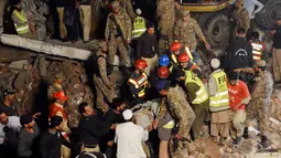 Tim SAR mengevakusi salah satu korban dari puing reruntuhan pabrik berlantai lima yang ambruk di Lahore, Pakistan Timur, Rabu (4/11) malam waktu setempat. Sedikitnya 16 orang tewas dan 40 luka-luka akibat kejadian tersebut. (AFP PHOTO/Arif Ali)