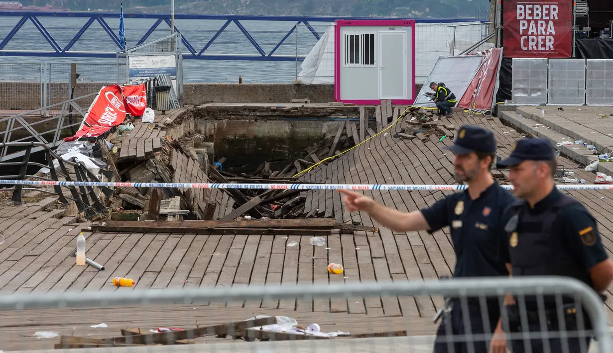 Petugas kepolisian berjalan dekat lokasi robohnya platform panggung dari kayu pada festival musik di tepi laut di Vigo, Spanyol, Senin (13/8). Penyebabnya ambruknya panggung sepanjang 30 meter dan lebar 10 meter itu belum diketahui. (AP/Lalo R. Villar)