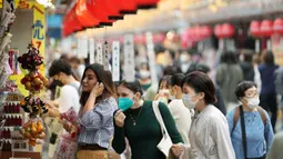 Turis asing berbelanja di toko suvenir dekat kuil Buddha Sensoji di distrik hiburan Asakusa, Tokyo, Jepang, Senin (17/10/2022). Pengunjung termasuk turis asing memadati distrik Asakusa setelah adanya pelonggaran pembatasan karena pandemi virus corona. (AP Photo/Hiro Komae)