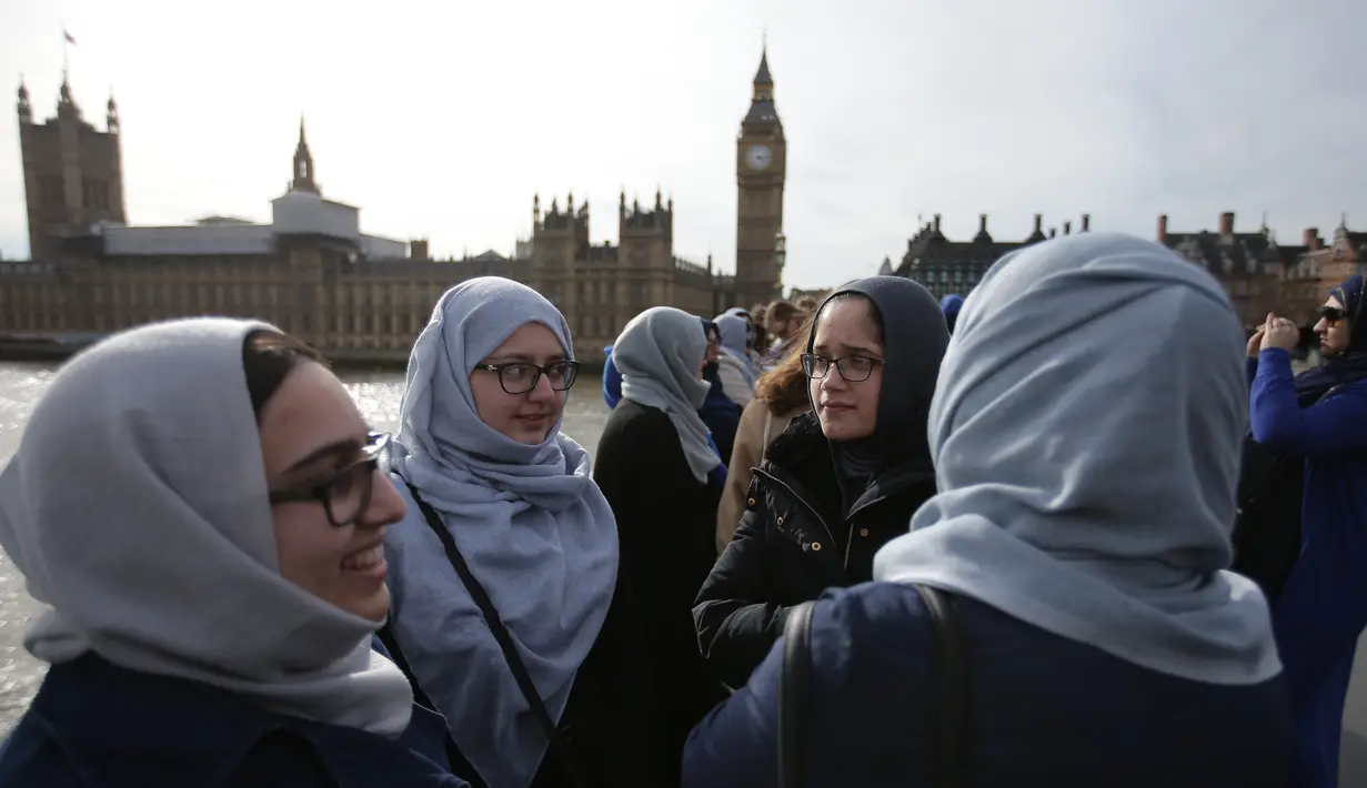 Puluhan perempuan dari beragam etnis berkumpul menggelar aksi solidaritas mengenang korban teror London di Jembatan Westminster, dekat Gedung Parlemen Inggris, Minggu (26/3). Aksi solidaritas dihelat oleh Women’s March di London. (Daniel LEAL-OLIVAS/AFP)