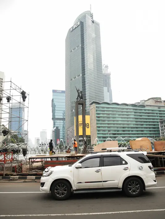 Kendaraan melintas dekat pembuatan panggung untuk acara malam tahun baru di sekitar kawasan Bundaran HI, Jakarta, Rabu (25/12/2019). Merayakan pergantian tahun, Pemprov DKI Jakarta menggelar sejumlah acara di sejumlah titik sepanjang Jalan Sudirman-MH Thamrin. (Liputan6.com/Faizal Fanani)