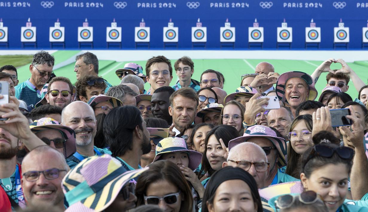 Presiden Prancis, Emmanuel Macron (tengah) berfoto bersama dengan para volunteer saat menyaksikan kompetisi panahan selama Olimpiade Paris 2024 di Esplanade des Invalides, Paris, Prancis pada 2 Agustus 2024. (AFP/Pool/Andre Pain)