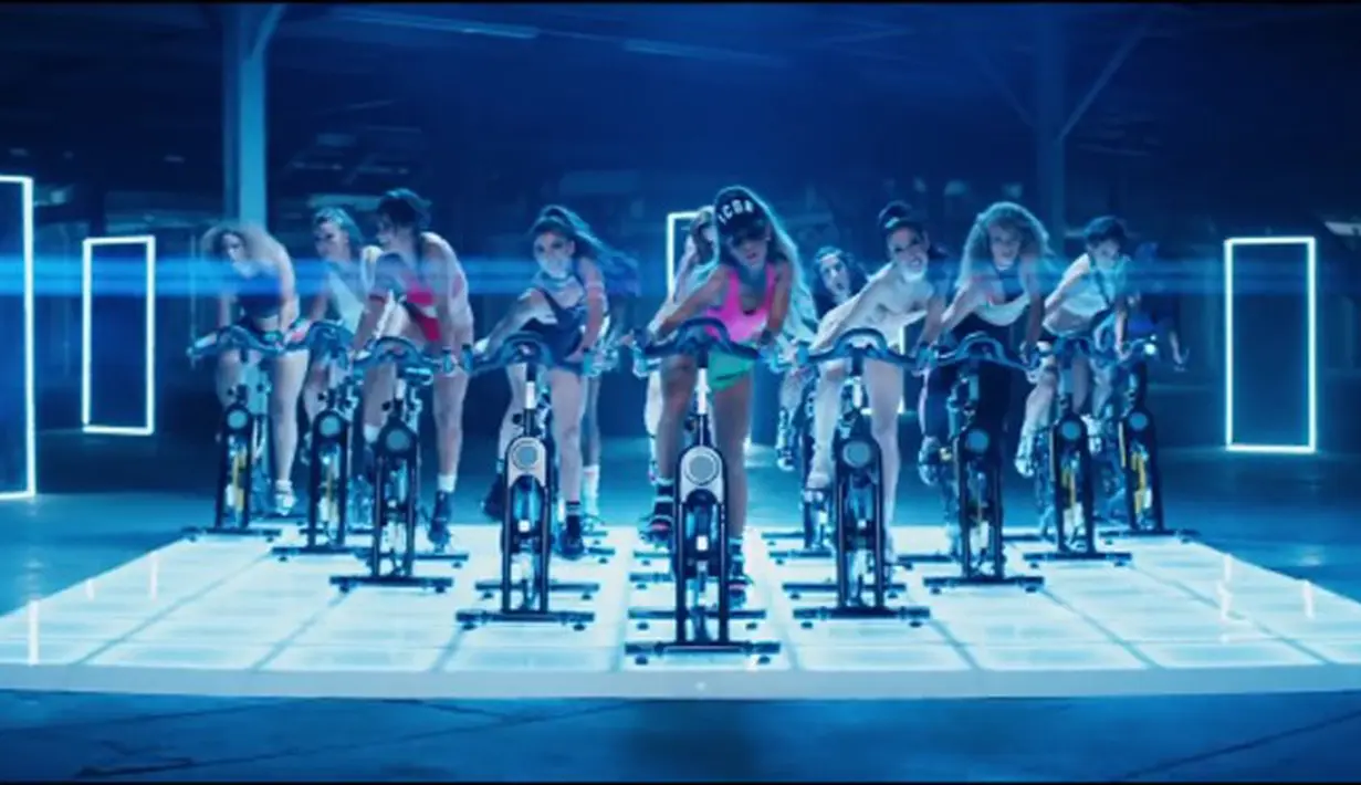 Dengan mengenakan topi, dan sneakers warna pink. Begitu juga dengan para penari latar lain yang kompak mengayuh sepeda di atas panggung. Didukung dengan tata cahaya yang apik. (youtube)