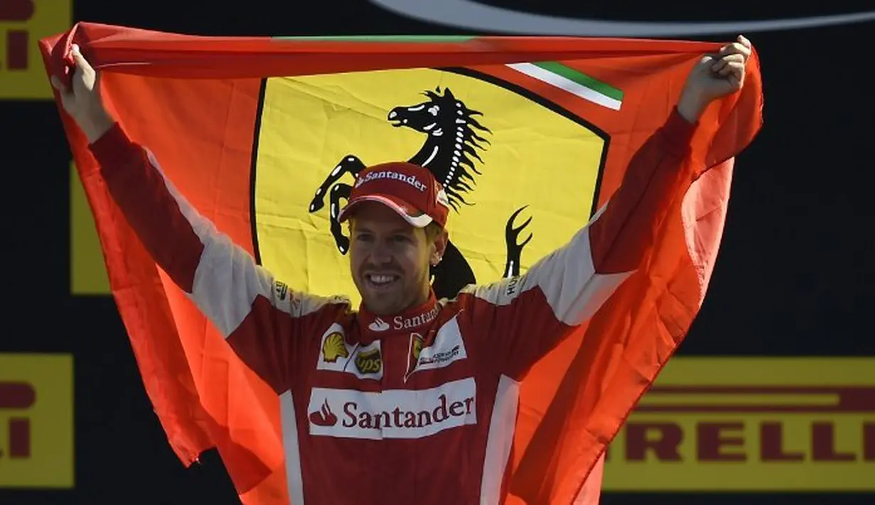 Sebastian Vettel dengan bendera Ferrari di podium pemenang Sirkuit Monza, Italia. Minggu (6/9/2015). (AFP Photo/Olivier Morin)