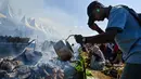 Seorang peserta mengisi tabung bambu dengan santan saat memasak lemang, hidangan nasi ketan tradisional yang dimasukkan ke dalam tabung bambu dan diisi dengan santan yang kemudian diletakkan di atas api, selama acara memasak massal di Blang Pidie, Kabupaten Aceh Barat Daya, Aceh, pada Sabtu 25 April 2026. (CHAIDEER MAHYUDDIN/AFP)