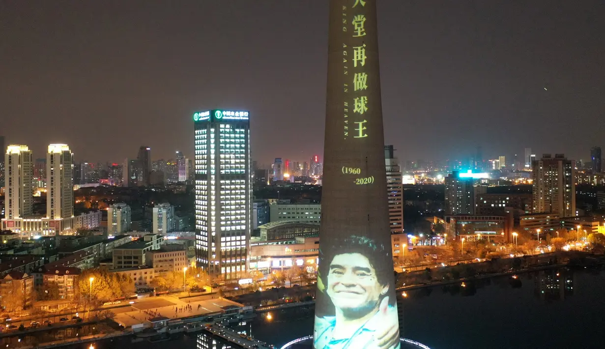 Foto udara menunjukkan mantan pesepak bola Argentina Diego Maradona diproyeksikan di Menara TV Tianjin di Kota Tianjin, China utara (26/11/2020). Maradona tutup usia di usia 60 tahun akibat serangan jantung pada Rabu (25/11). (Xinhua/Li Ran)