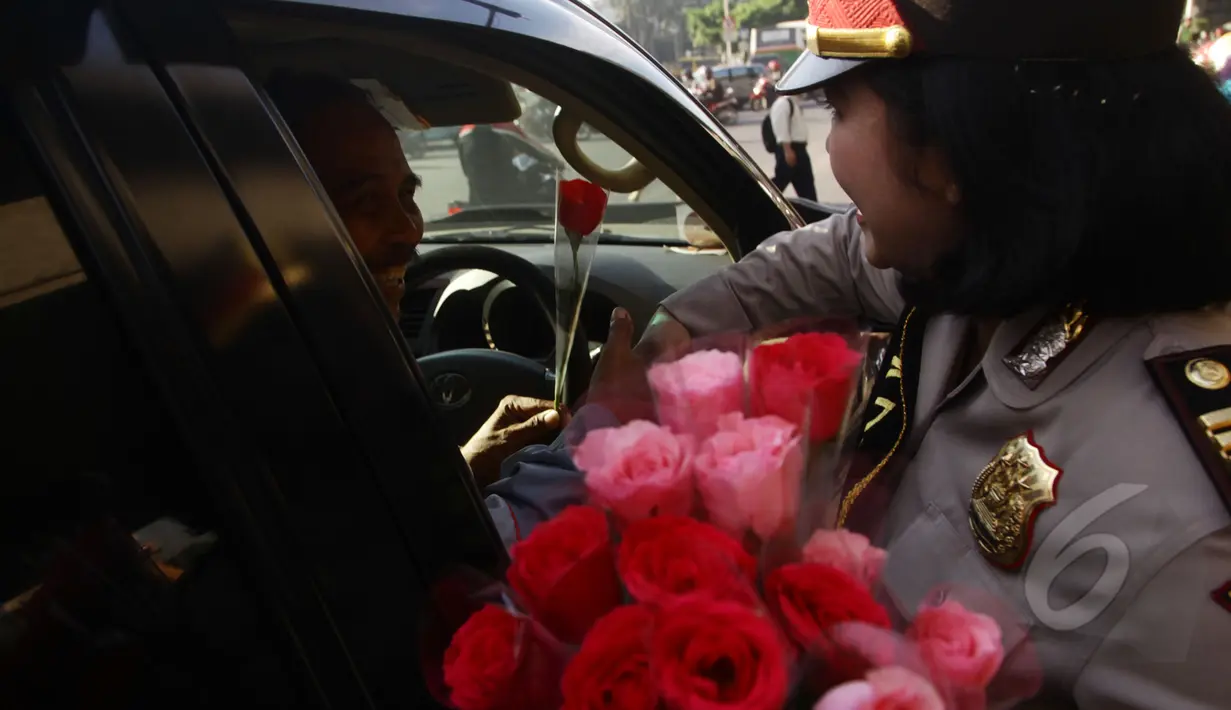 Pengendara mobil mendapat bunga dari seorang Polwan saat melintas di kawasan Slipi, Jakarta, Selasa (21/4/2015). Pembagian bunga ini dalam rangka memperingati hari Kartini.(Liputan6.com/Johan Tallo)