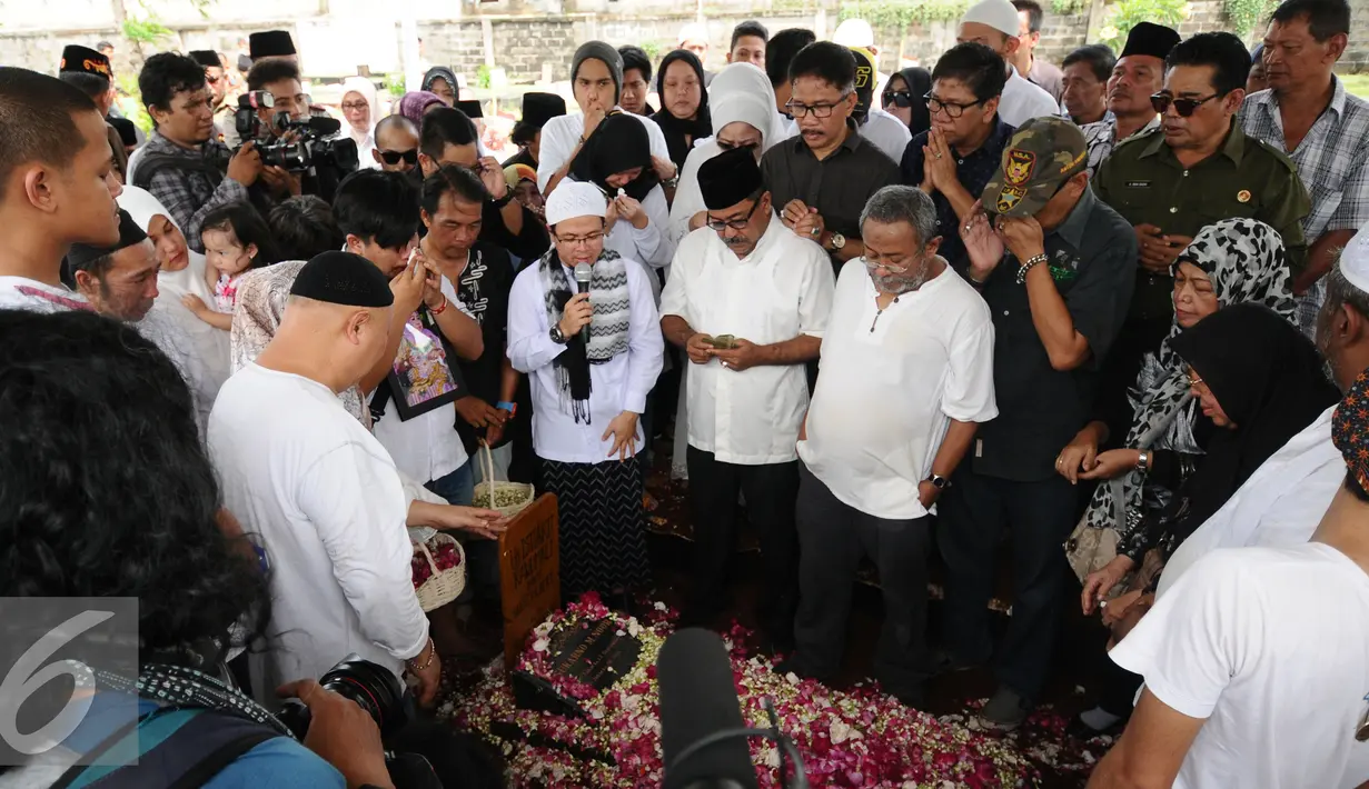 Gubernur Banten, Rano Karno (berpeci) saat membacakan doa pada pemakaman ibunya, Lily Soekarno M Noor di TPU Tanah Kusir Jakarta, Senin (7/12/2015). Ibunda Rano Karno wafat di usia 77 tahun akibat komplikasi penyakit. (Liputan6.com/Helmi Fithriansyah)