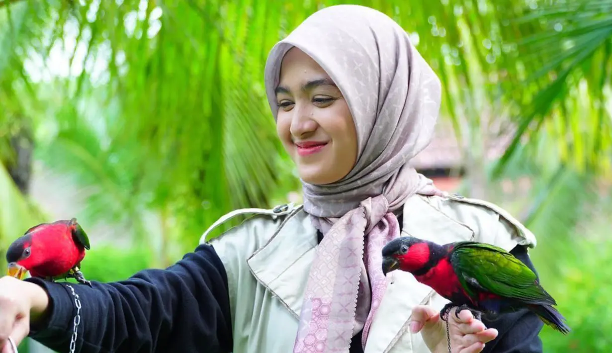 Cut Syifa terlihat manis mengenakan hijab dengan model yang dibentuk seperti pita di bagian depan. Dalam foto ini Cut Syifa berfoto bersama dua burung yang ia beri nama Kimmy dan Dido. (Instagram/@cutsyifaa)