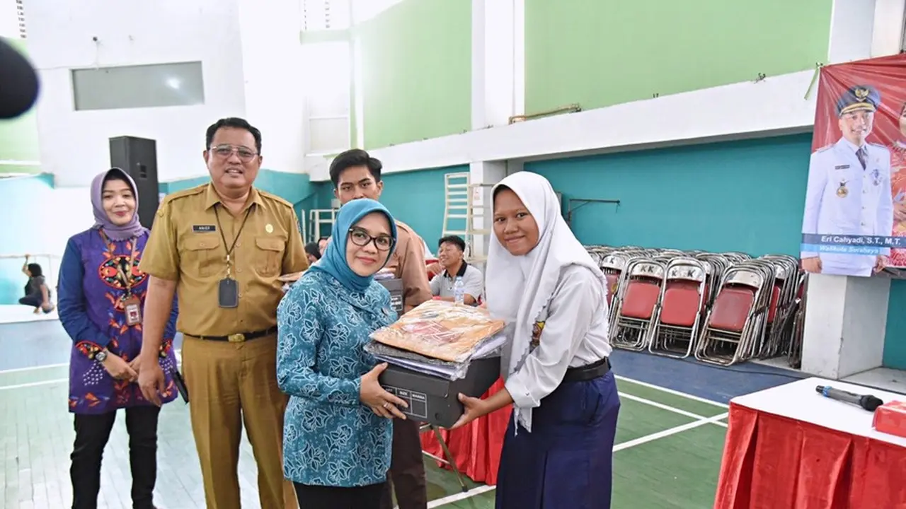 Ketua Tim Penggerak (TP) PKK Surabaya Rini Indriyani secara simbolis membagikan seragam dan sepatu sekolah kepada sejumlah perwakilan pelajar penerima. (Istimewa)