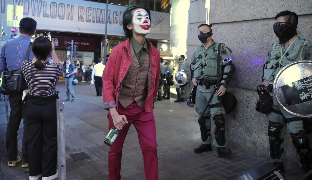 Demonstran Berkostum Halloween: Pria berkostum Halloween berjalan melewati polisi di Hong Kong, 31 Oktober 2019. Para pemrotes Hong Kong menyerukan untuk merayakan Halloween dengan mengenakan topeng yang menggambarkan pejabat pemerintah atau tokoh-tokoh menakutkan. (AP Photo/Kin Cheung)