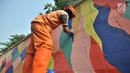 Petugas PPSU mengecat saat pembuatan mural pada tembok yang berada di pinggir Jalan Landasan Pacu, Jakarta, Rabu (11/7). Pengecatan dan pembuatan mural ini dalam rangka mempercantik kawasan serta menyambut Asian Games 2018. (Merdeka.com/Iqbal S. Nugroho)