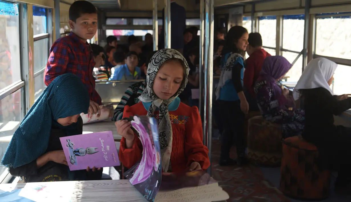 Anak-anak Afghanistan membaca buku dalam bus yang dijadikan perpustakaan keliling di Kabul, 4 April 2018. Bus umum yang telah diubah fungsi dan bentuknya tersebut memberikan kebahagiaan tersendiri bagi anak-anak Afghanistan. (AFP/Shah MARAI)